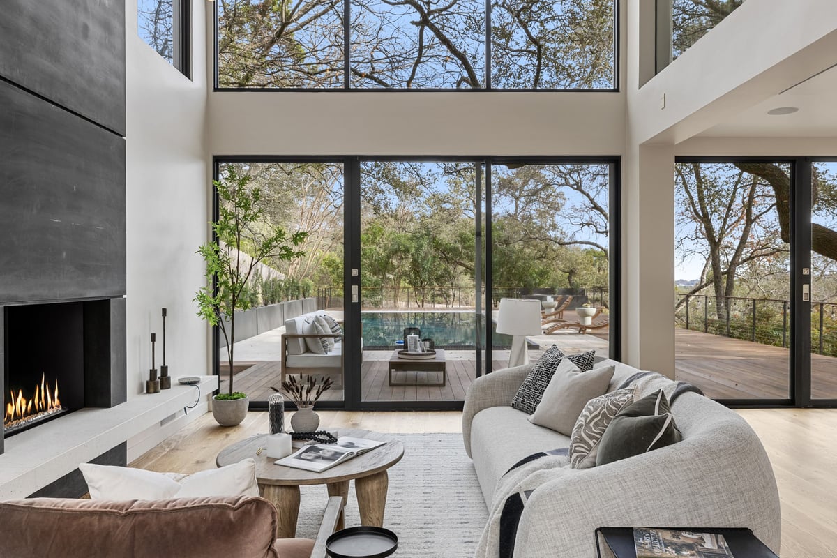 The living room with a fireplace and glass walls to the pool