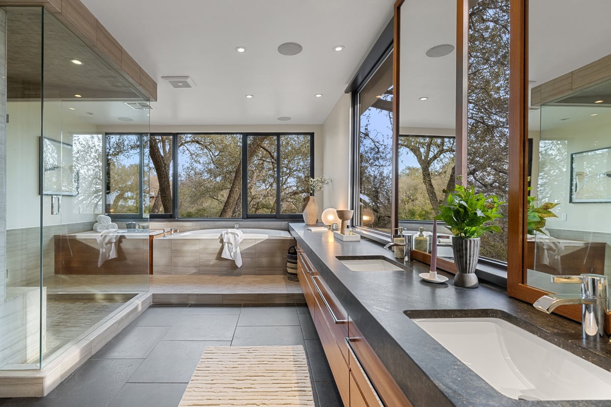 The primary bath with a soaking tub, vanity and glass shower