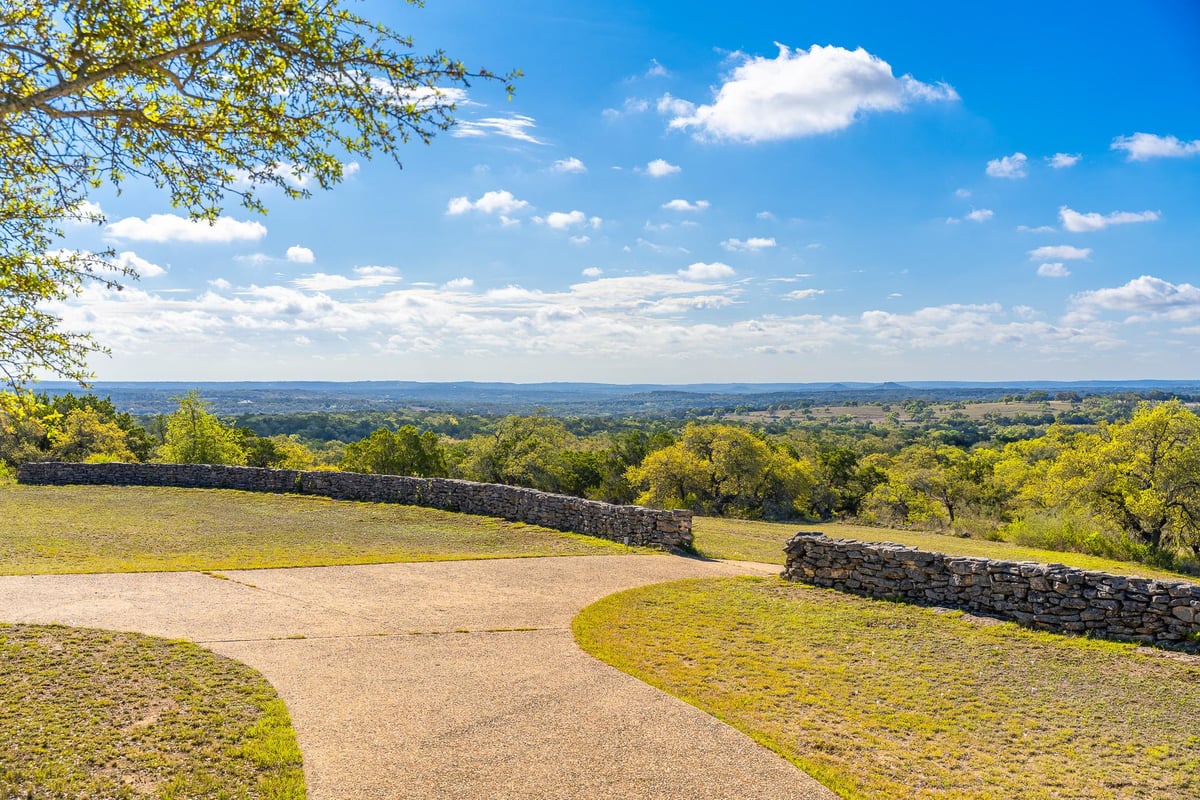 View 1100 Pump Station Rd in none 1100 Pump Station Rd - view with long Hill Country view and curved drive - Luxury home in none, Wimberley, TX
