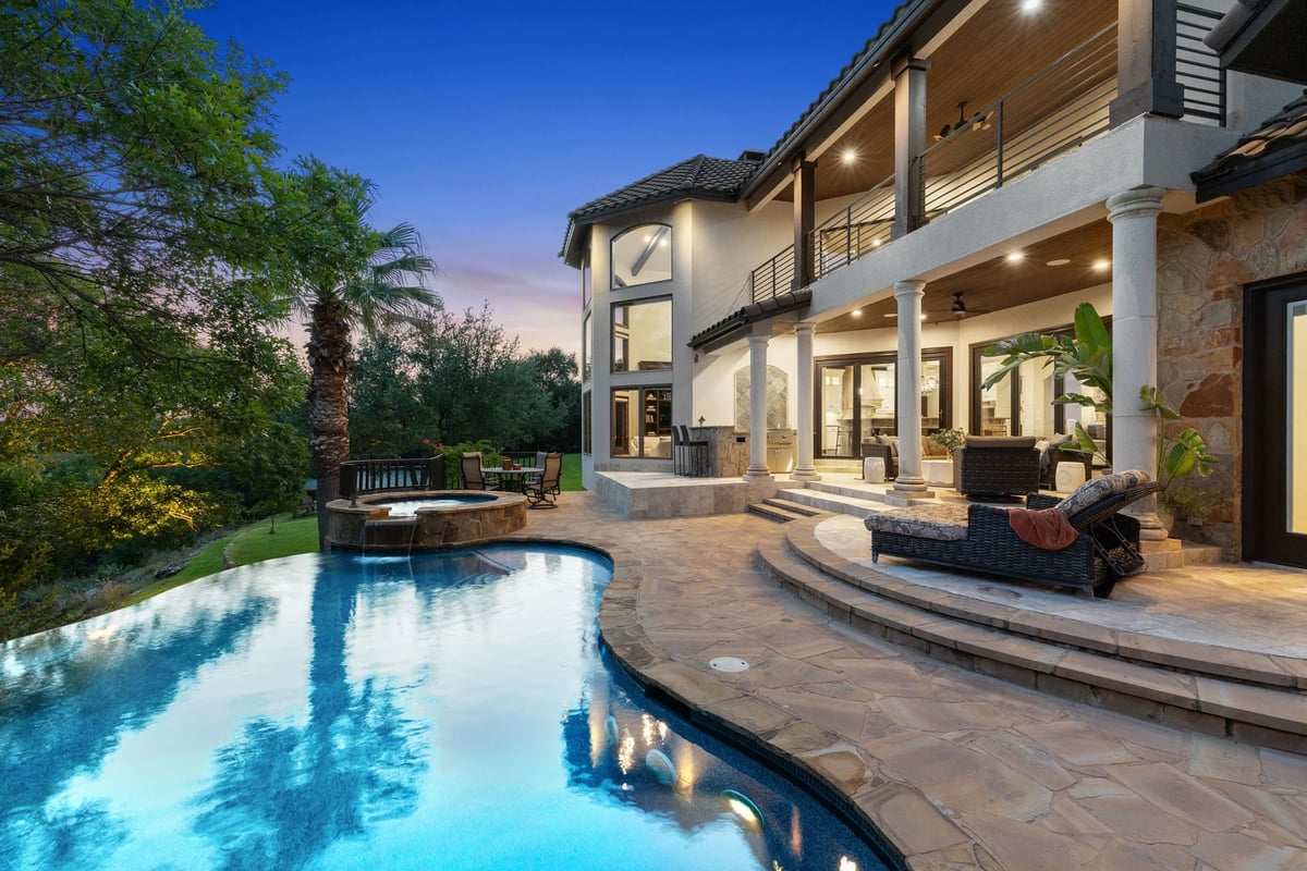 Twilight pool deck with infinity-edge pool, spa, and covered two-story porch