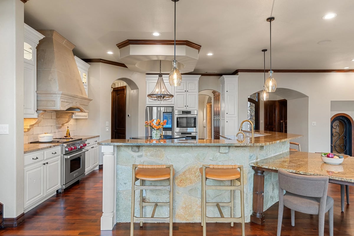 Kitchen with Wolf range, carved stone hood, and beaded chandelier