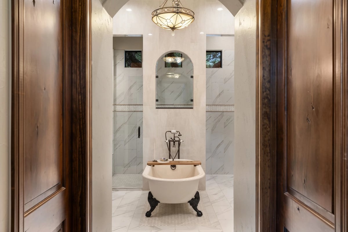 Primary bath with clawfoot soaking tub and marble-tiled walk-in shower