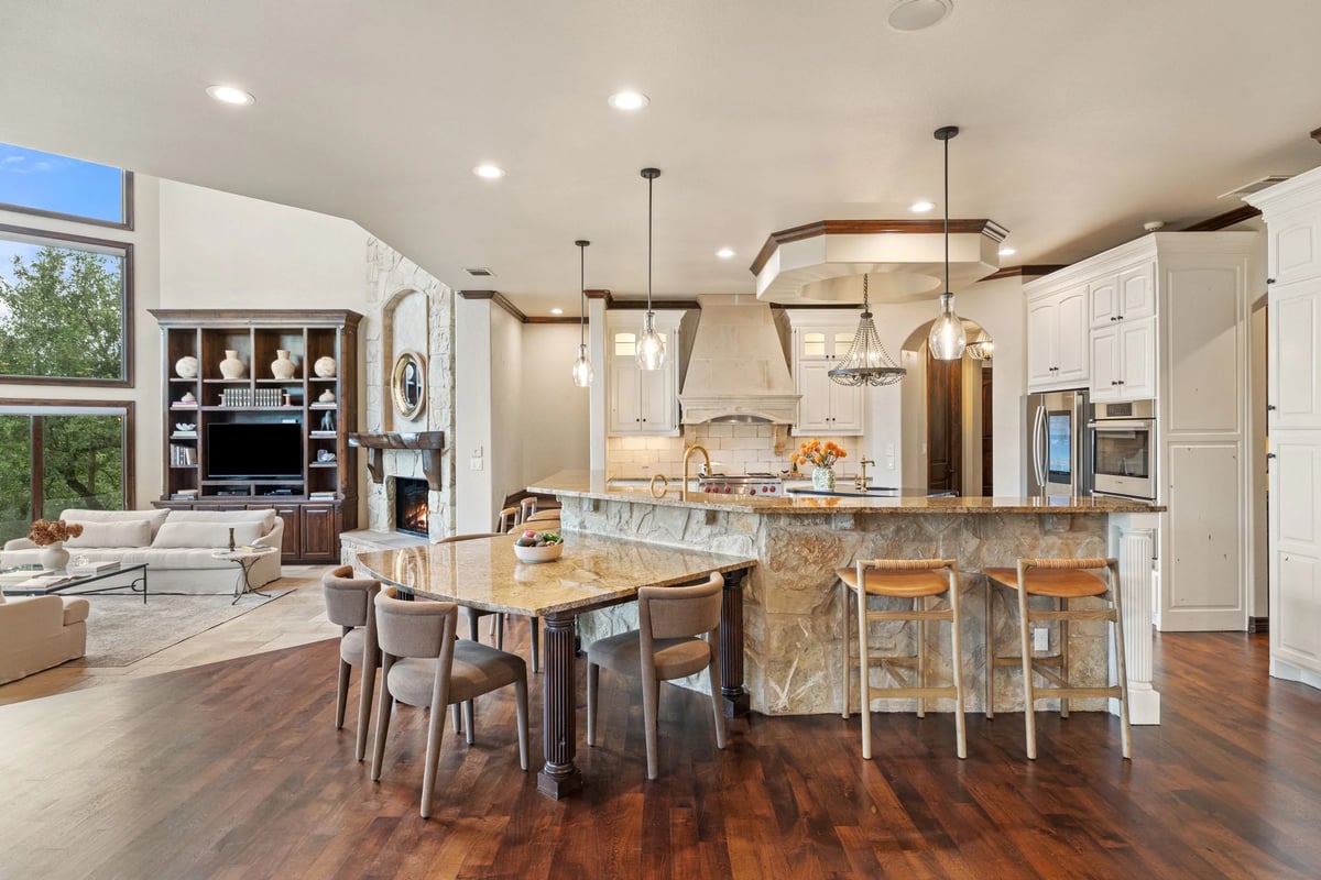 Open kitchen, breakfast bar, and living room fireplace under one vaulted great room