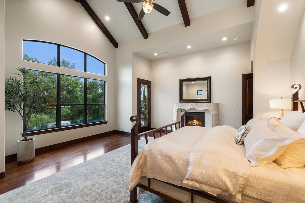 Primary bedroom with beamed ceiling, fireplace, and doors to the balcony