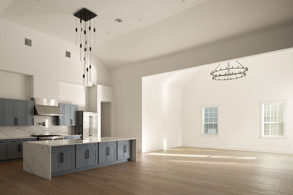 Kitchen island opening to the former church hall under a wrought-iron chandelier