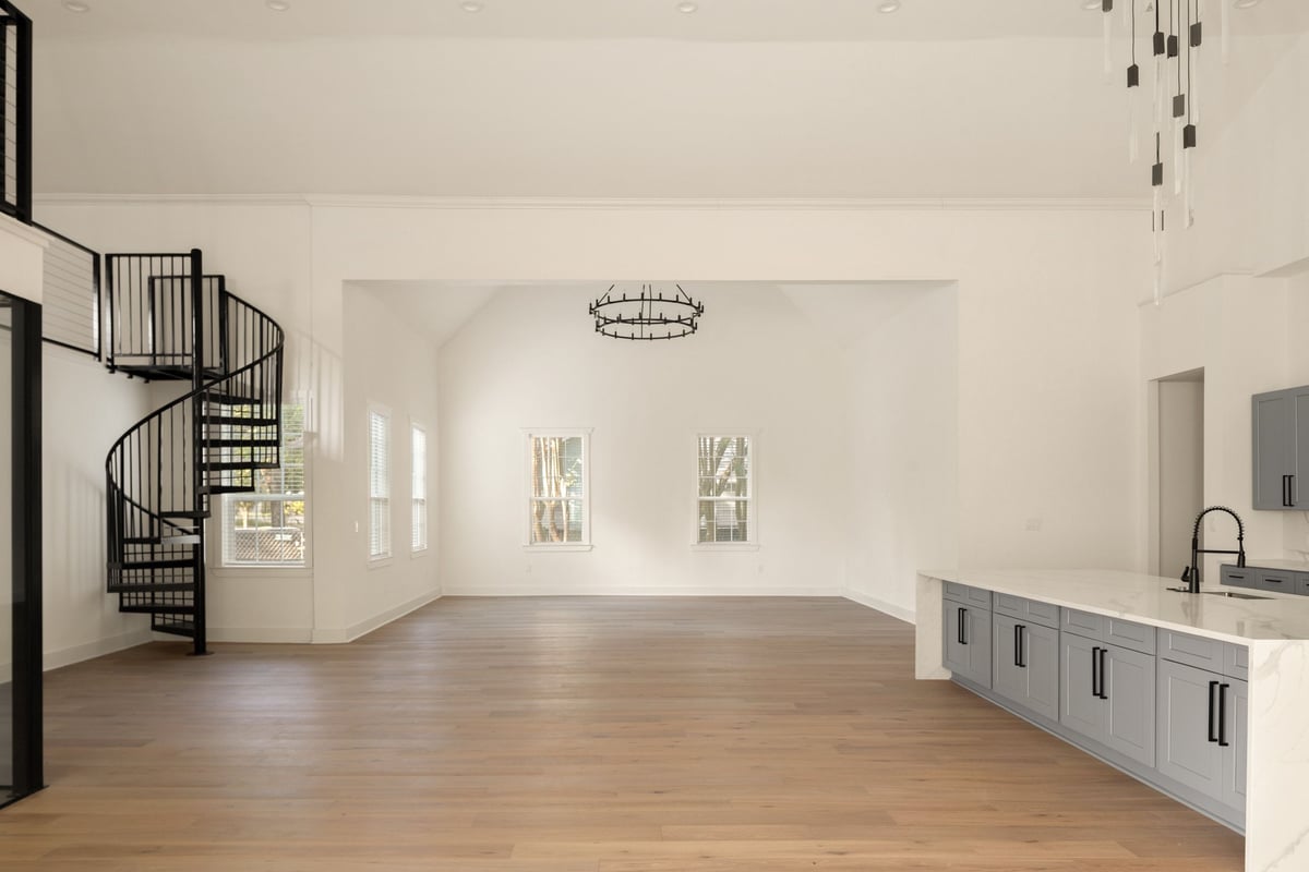 Open living space with a black spiral stair and a chandelier in the former church hall