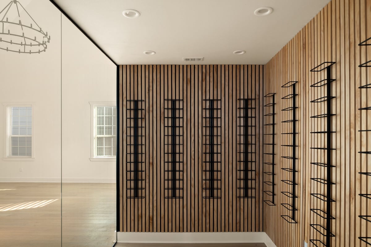 Wine display with wood-slat walls and black metal racks behind glass
