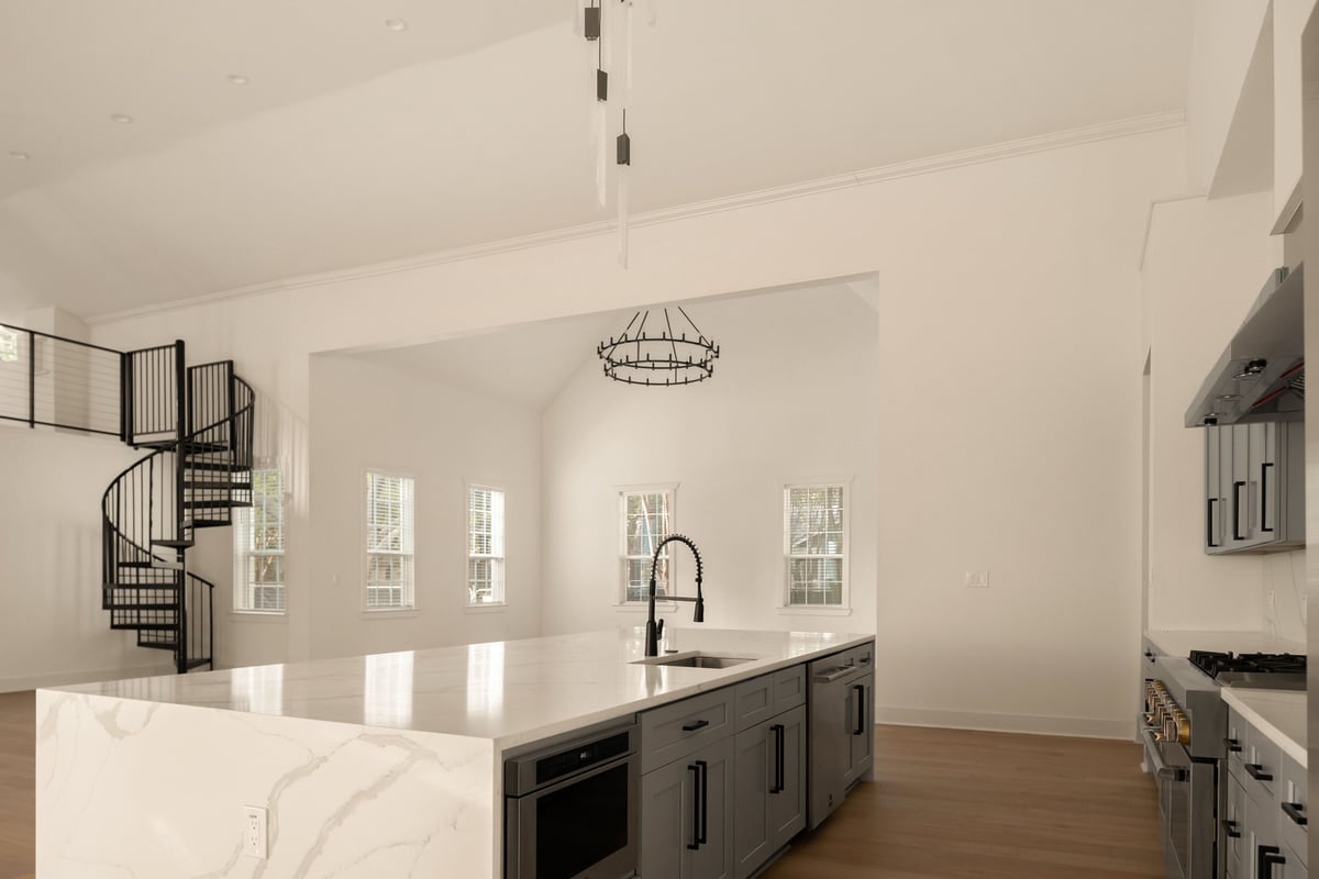 Kitchen island with a waterfall stone edge facing the living space and spiral stair