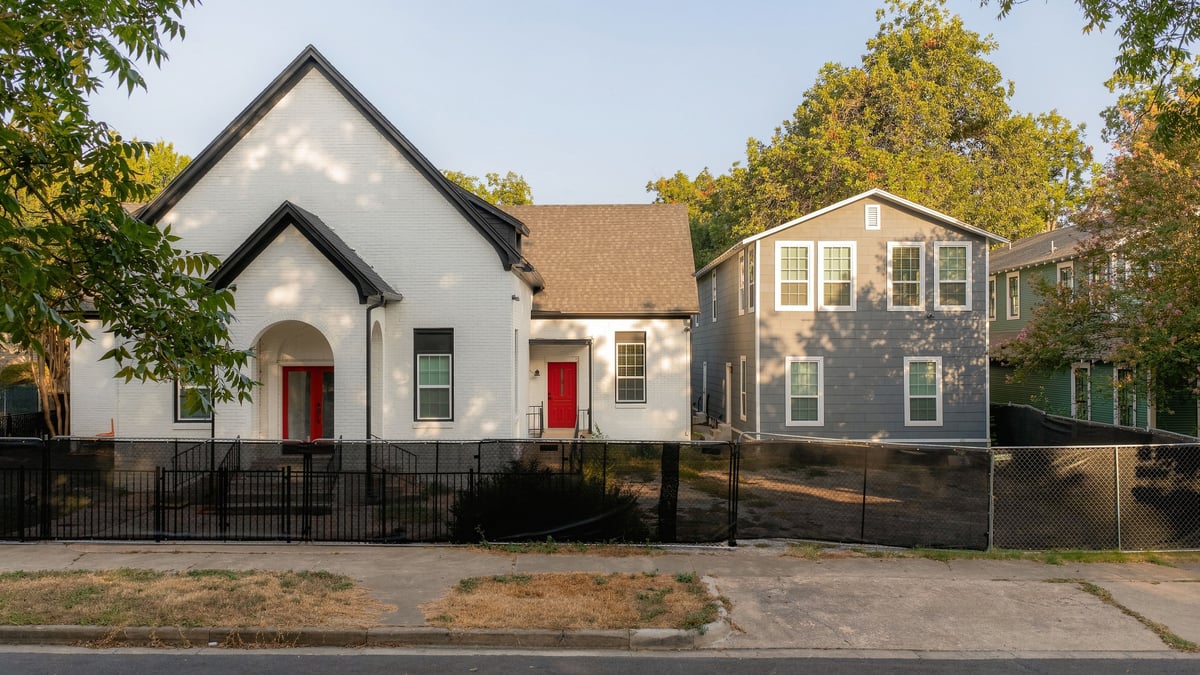 The church and the fourplex side by side, each with a red front door
