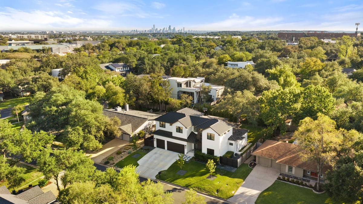 Aerial view over Northwest Hills toward the downtown Austin skyline, with the home in the foreground