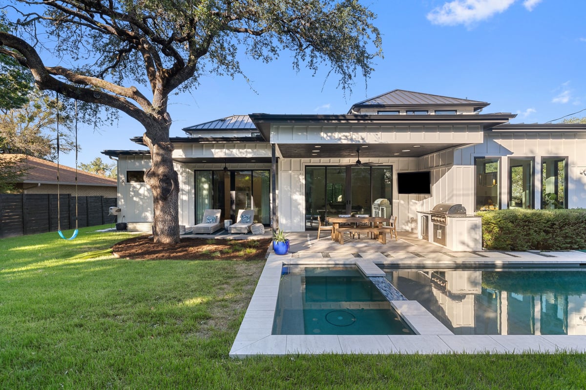 The rear of the home under a live oak, with the pool and spa in front