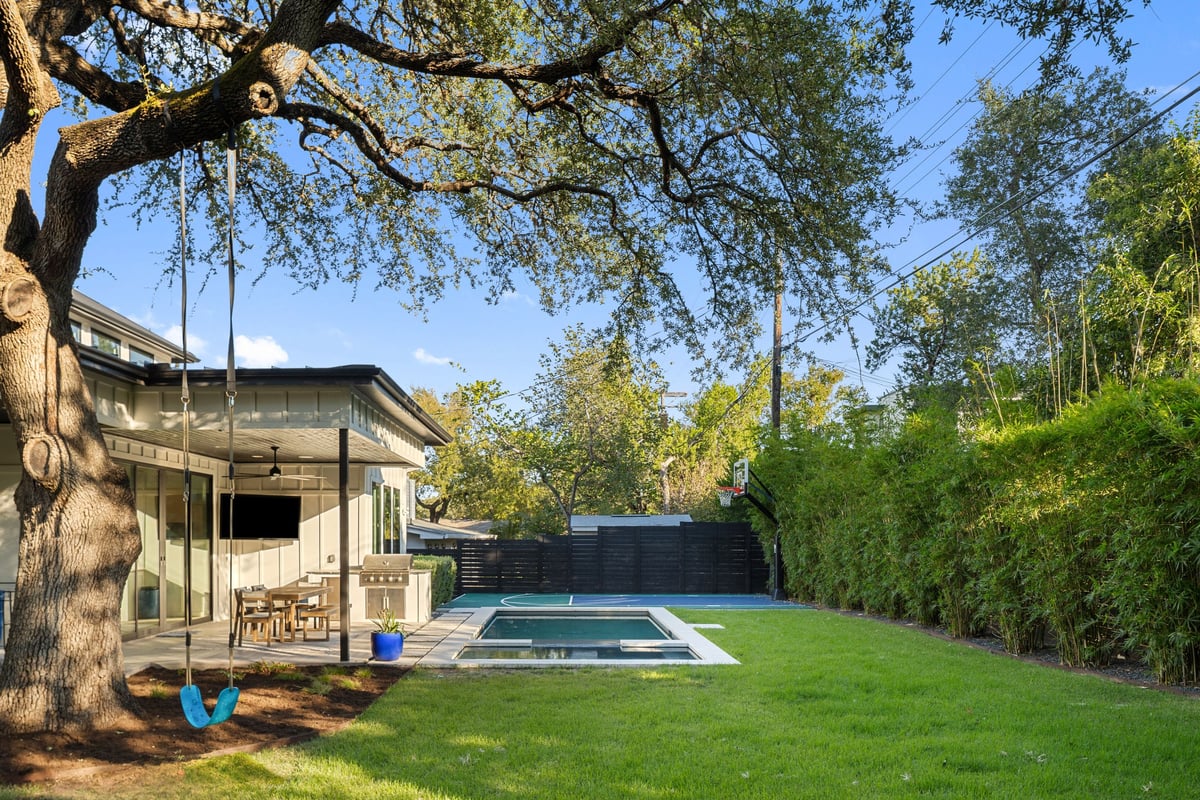 The live oak, rope swing and covered patio, with the pool at the far end of the lawn