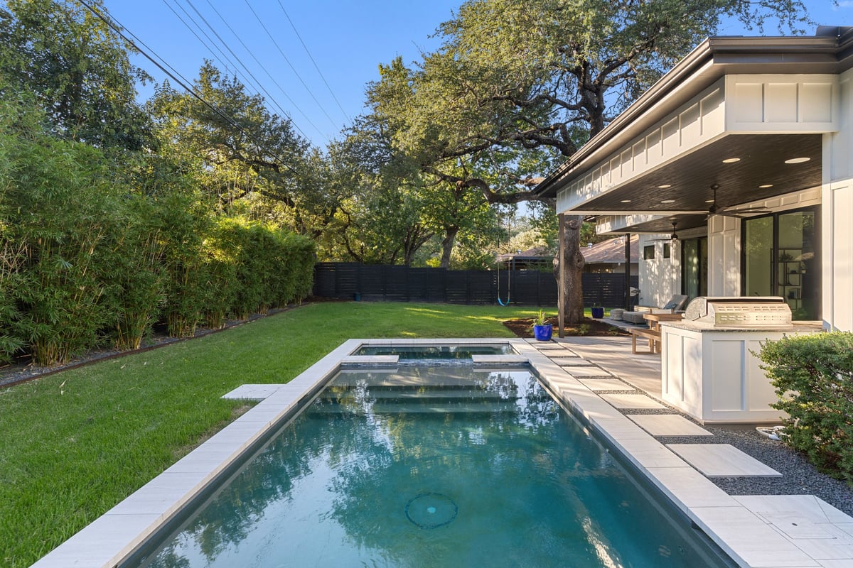The pool and spa running along the covered outdoor kitchen