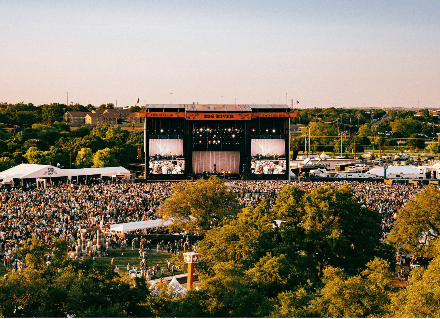A large crowd facing an outdoor concert stage.