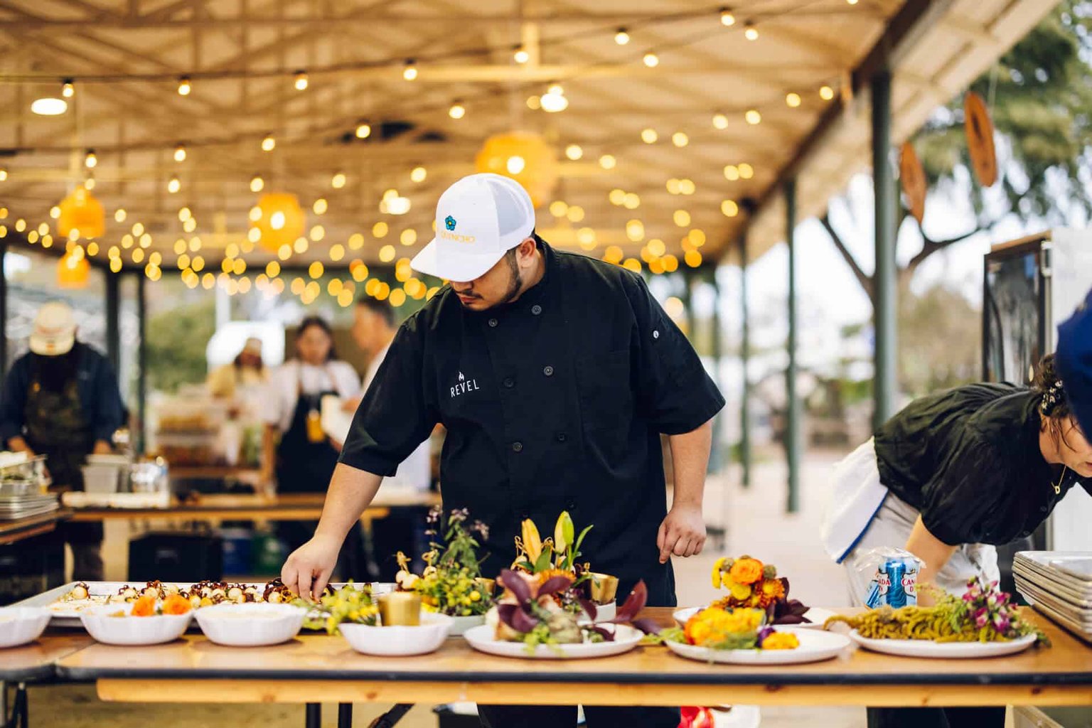 A cook preparing food at an outdoor dining event.