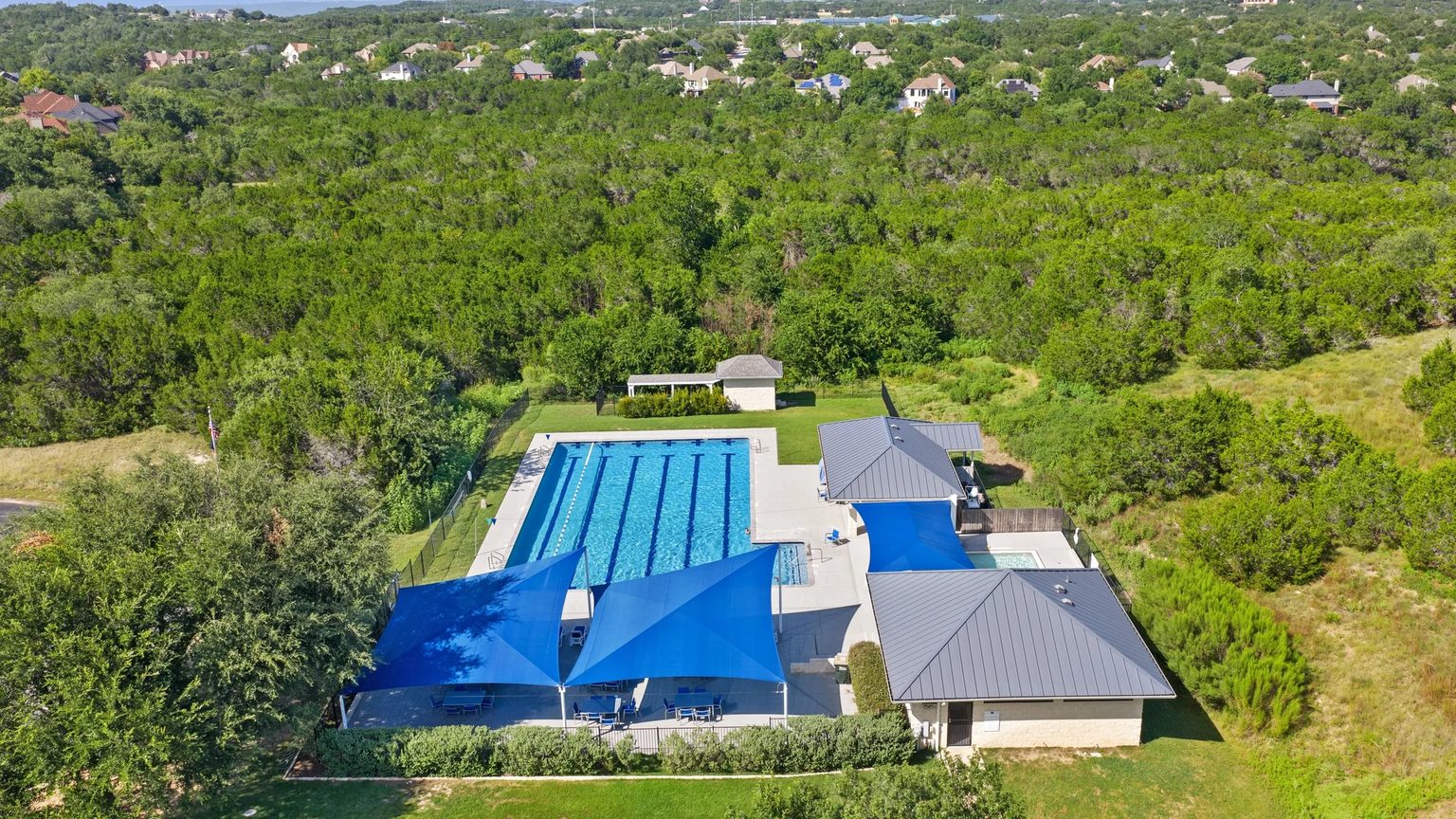The six-lane lap pool and shaded deck at Barton Creek West, surrounded by oak canopy