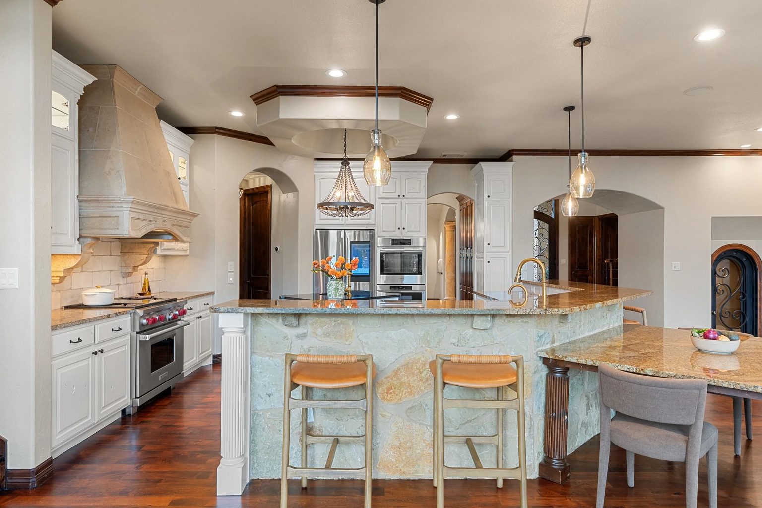 Kitchen with a Wolf range, carved stone hood and beaded chandelier at a Keenan Group listing
