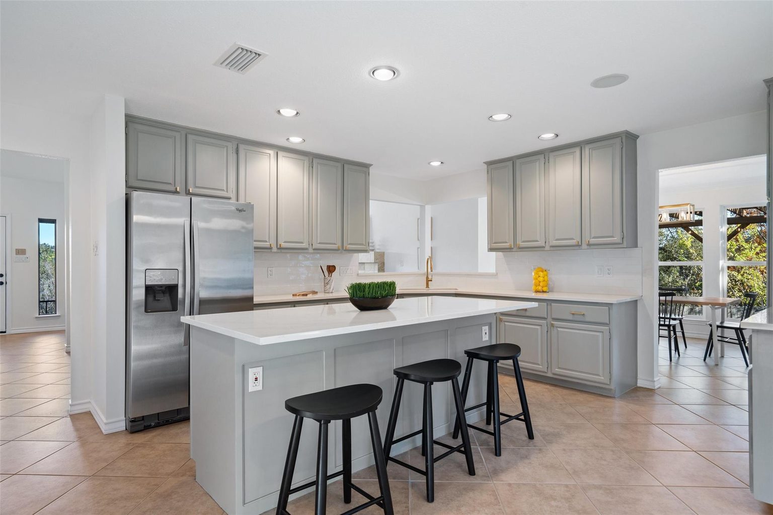 Refreshed kitchen with gray cabinets, white counters and island seating