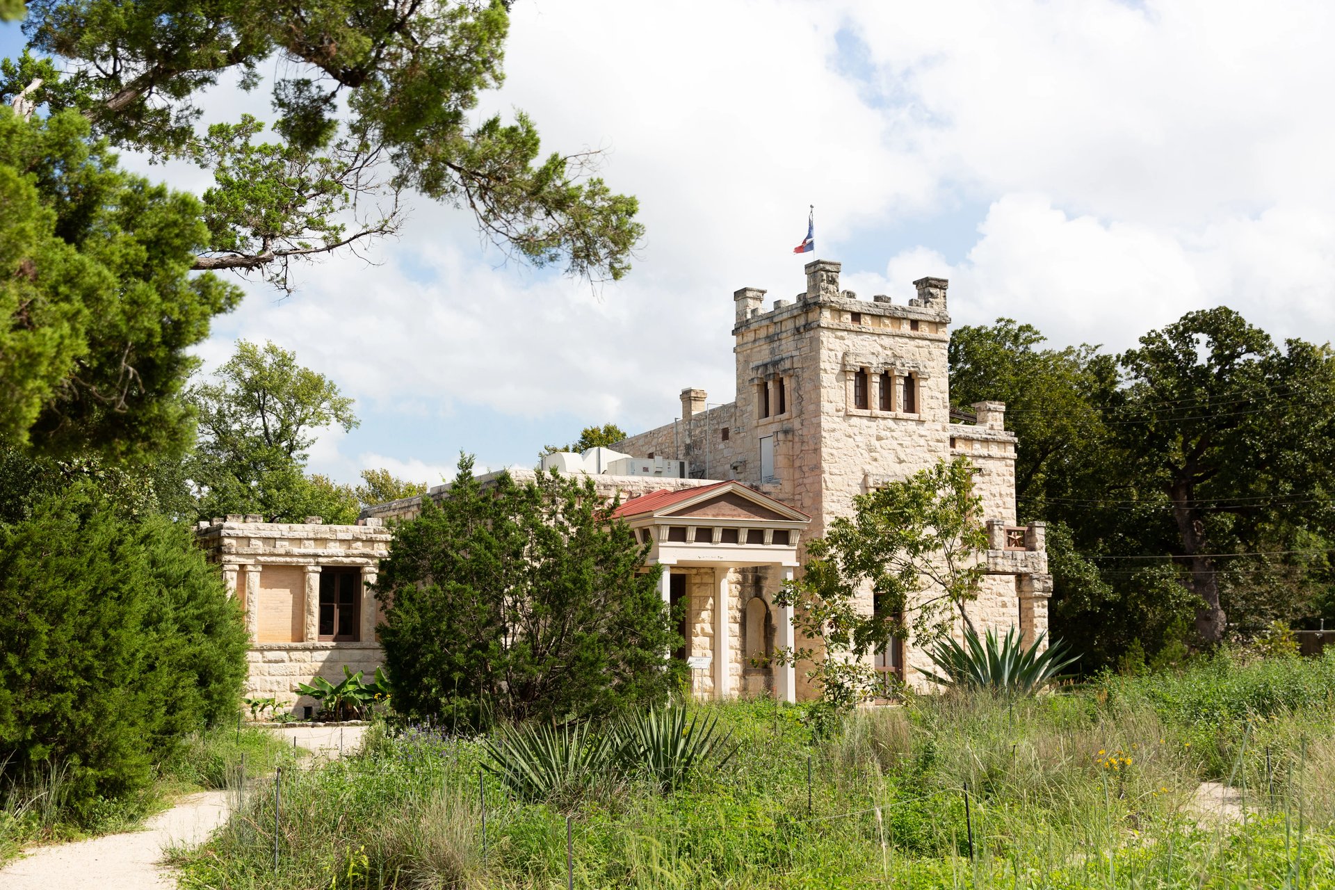 Elisabet Ney Museum's limestone building and tower behind native grasses in Hyde Park, 78751, Austin