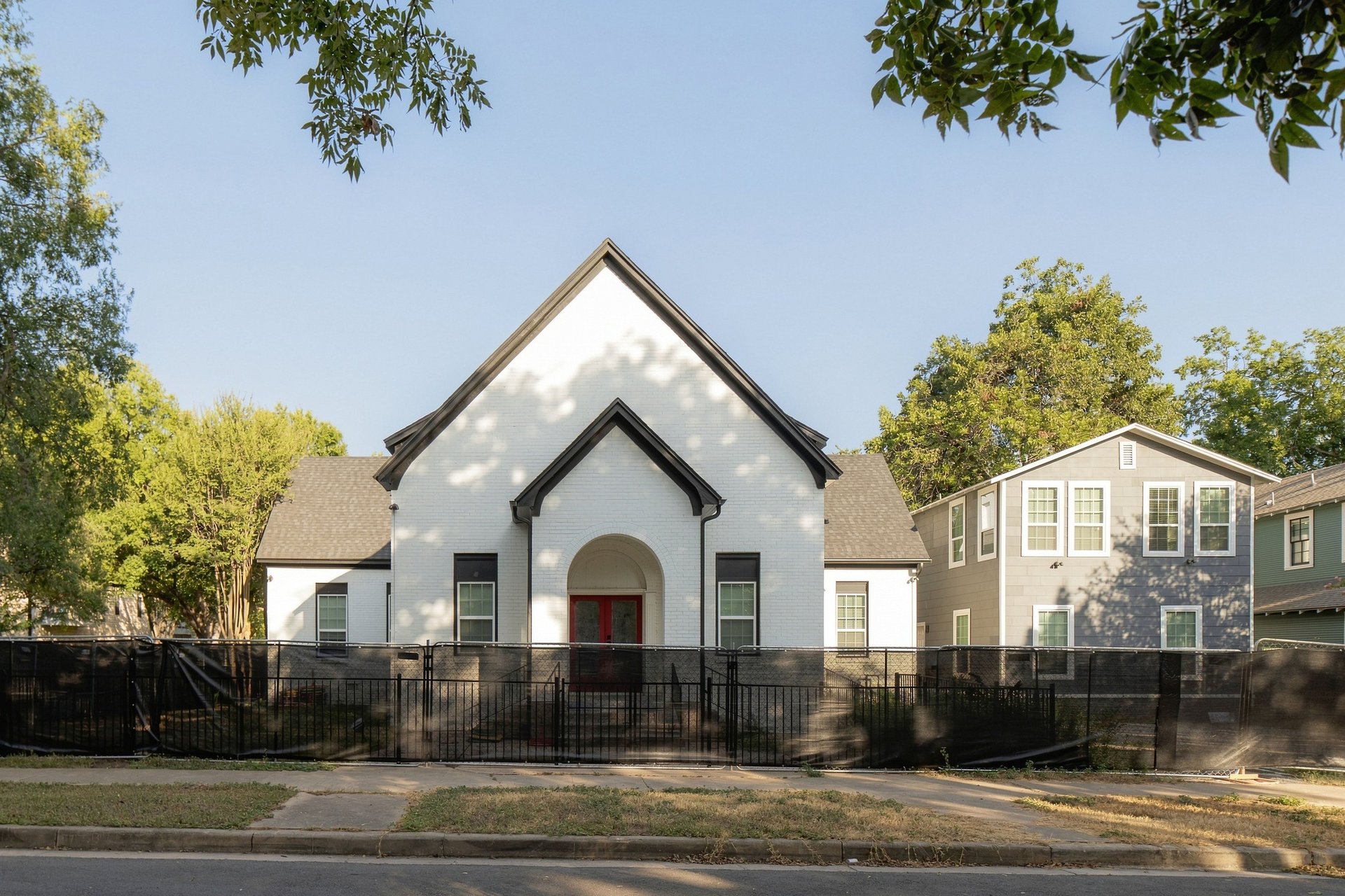 4115 Avenue D: the former church front with its arched entry and red doors, the fourplex to the right