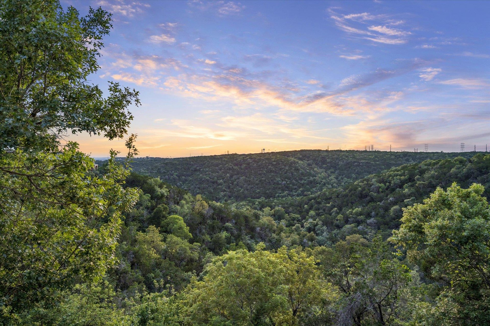 Sunset view across a wooded Hill Country canyon from a lot in River Place