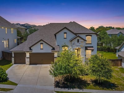 Front exterior with twilight curb appeal and stone facade at 15504 Cabrillo Way - 4 bed 3 bath home