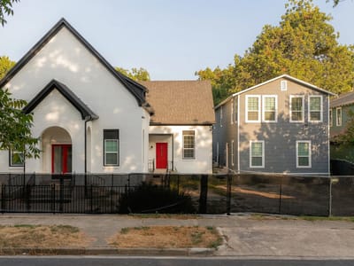 The church and the fourplex side by side, each with a red front door