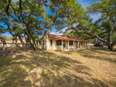 Front exterior with stone ranch house and wraparound porch at 518 Curly H Ranch Rd - 3 bed 2 bath home