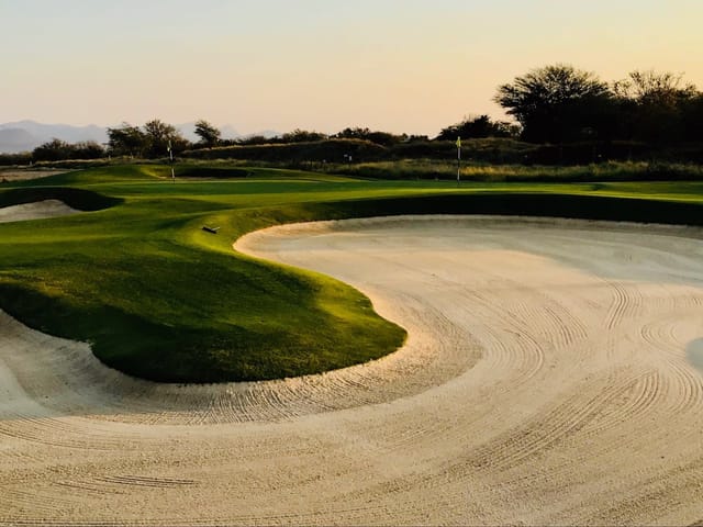 Raked sand bunkers surrounding golf-course greens at sunset