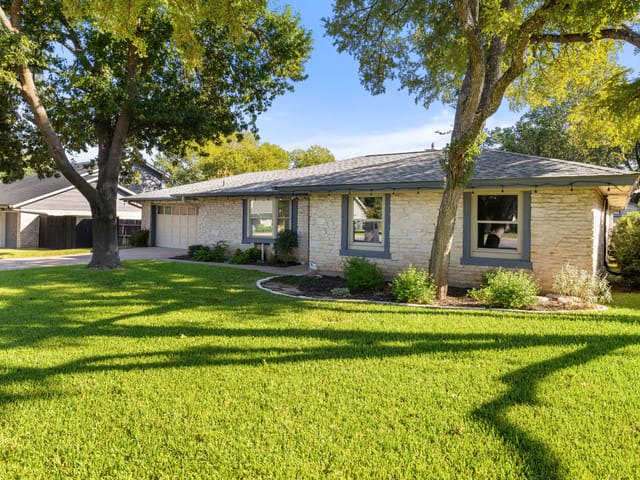 Front elevation under mature oaks at 1105 Deep Wood Drive, Round Rock