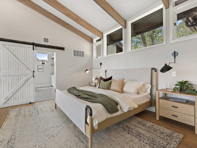 Vaulted bedroom with exposed beams and a barn door at 6905 Ladera Norte, Austin
